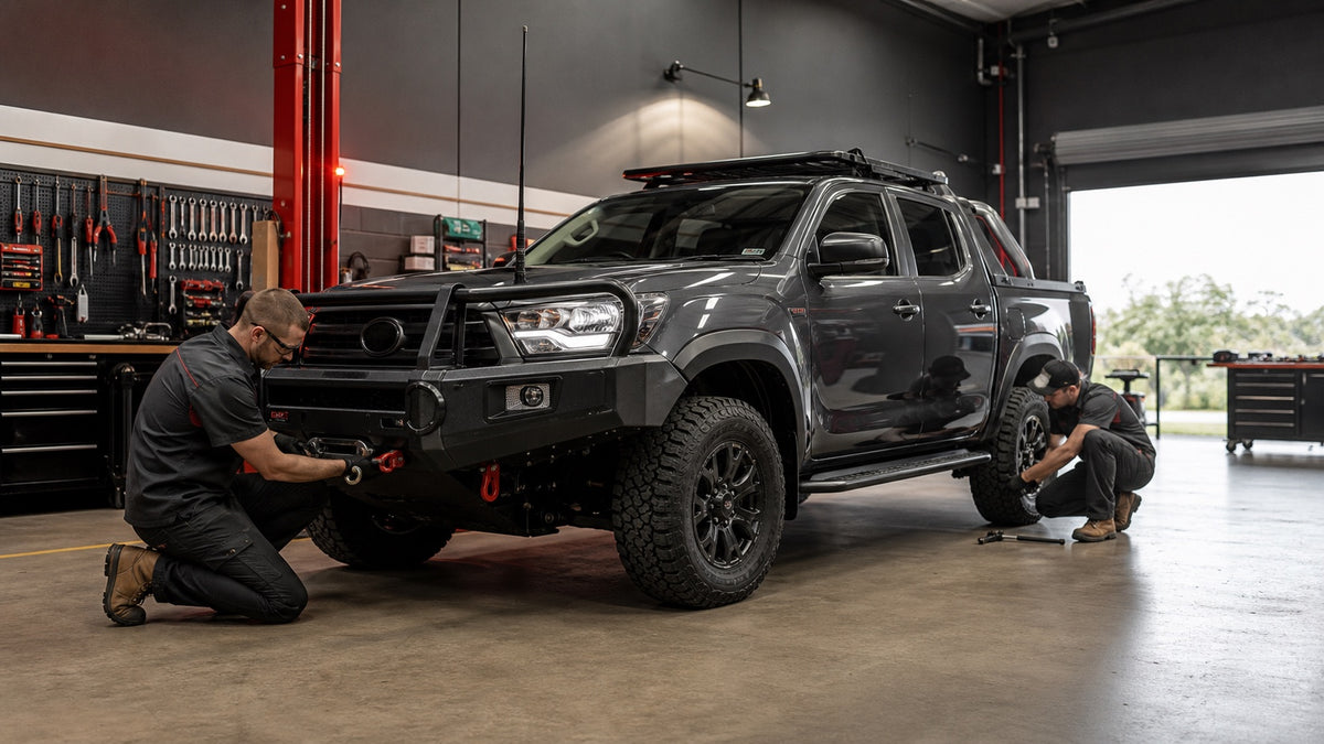 Illustrative workshop scene showing mechanics upgrading a premium dual-cab 4x4